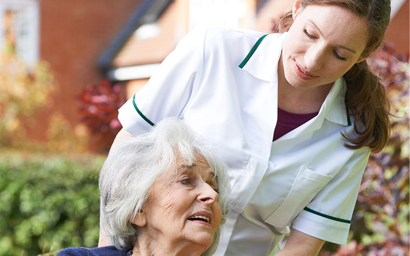 Seniorin im Rollstuhl mit Pflegerin